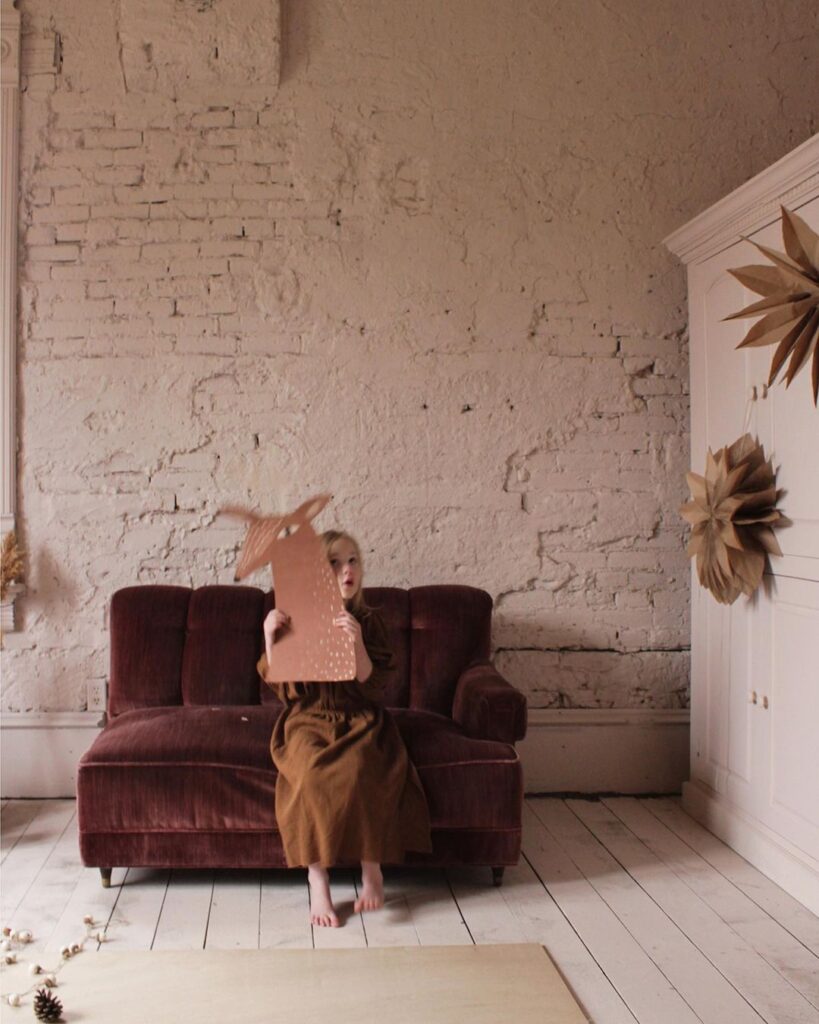 Tête de renne réalisée en papier, tenue par un enfant.