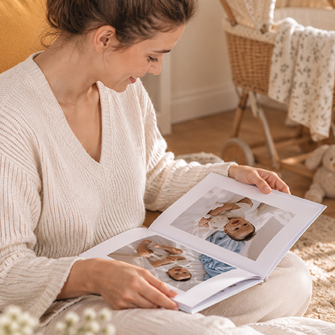 Jeune maman qui feuillette un album photo de naissance