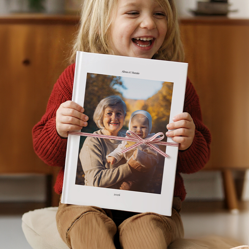 Petite fille qui montre un album photo avec un portrait de sa grand-mère